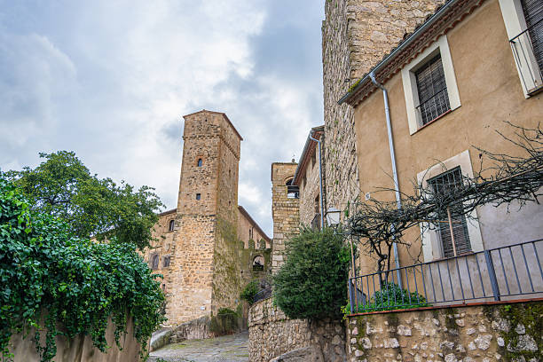 Narrow street view of ancient stone buildings and towers in the historic town of Trujillo Spain under a cloudy sky.