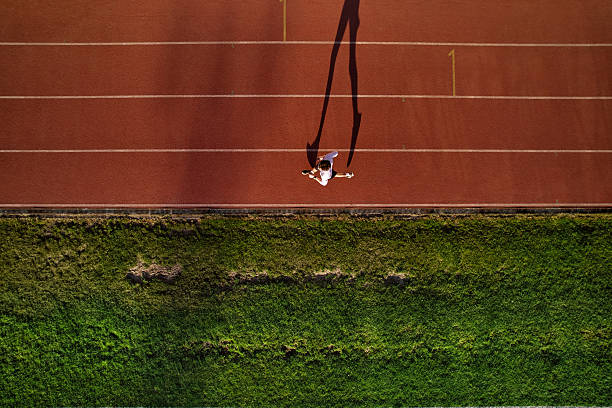 istock Man running alone on track, aerial view with dramatic shadow 2224298117