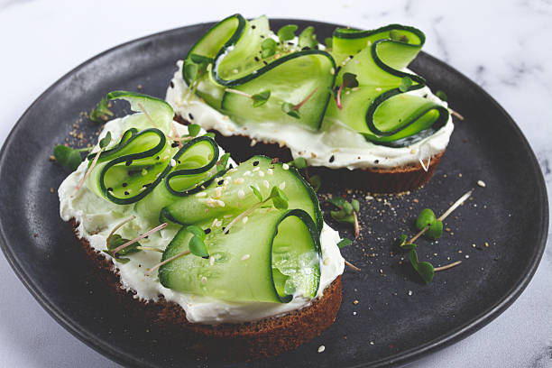 istock Breakfast, grain bread sandwiches, cream cheese, sliced cucumber, with microgreens, and sesame seeds, on a light table, close-up, top view, selective focus, no people, 2224298934