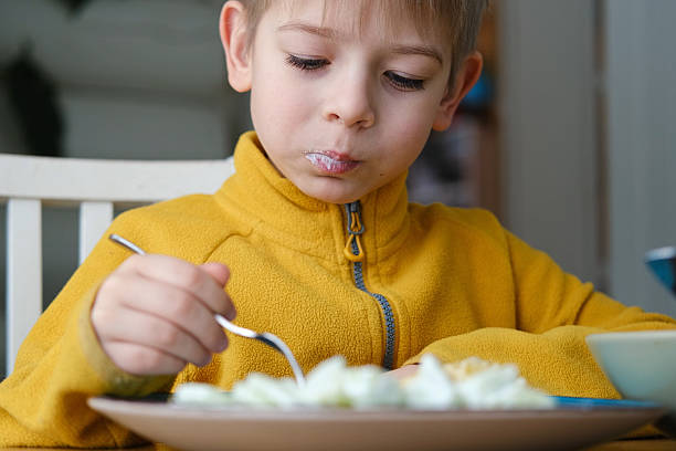 istock 6 years old boy eats pasta with cheese from blue plate. Child is eating spaghetti. Lunch time. Good appetite. Tasty children food. Close-up portrait. Carbs dinner. Fast food. Kid eating with fork. 2224305867