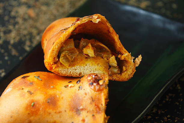 Close-up of freshly baked vegetable-stuffed makhani roll buns, topped with herbs and spices, served on a black platter. Perfect fusion of Indian flavors and bakery style.