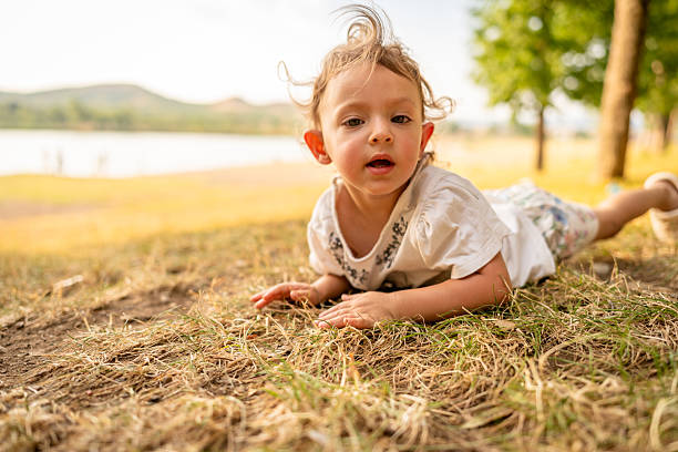Baby girl lying on the grass near Lake enjoying fresh air