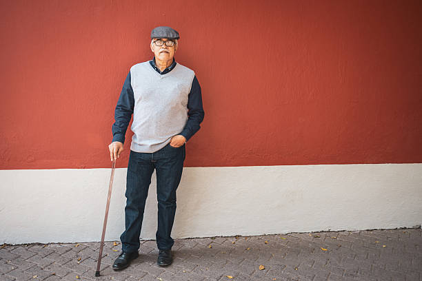 istock Senior man with walking cane leaning against red wall 2224311387
