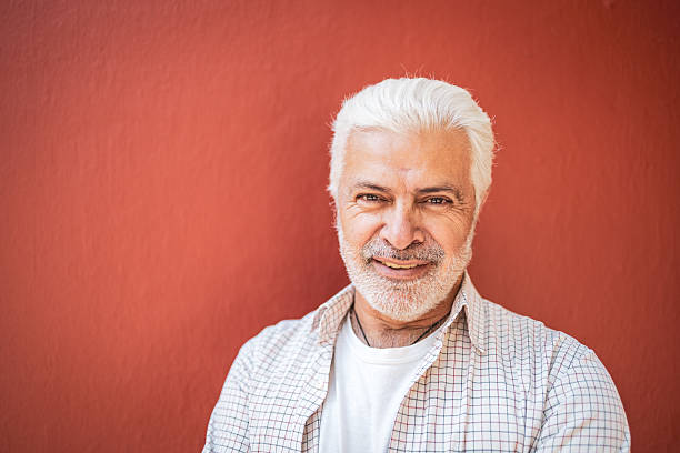 istock Confident senior man smiling against red wall 2224311388