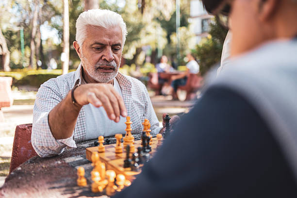 istock Senior man playing chess with friend in park 2224311431