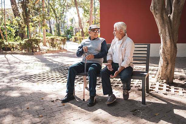 istock Two senior men sitting on bench and talking in the park 2224311494
