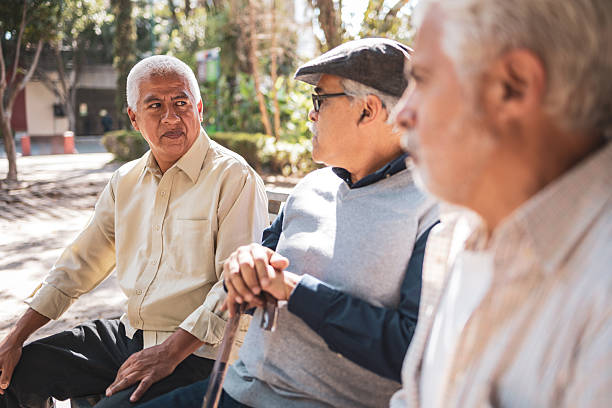 istock Elderly friends enjoying conversation on park bench 2224311501