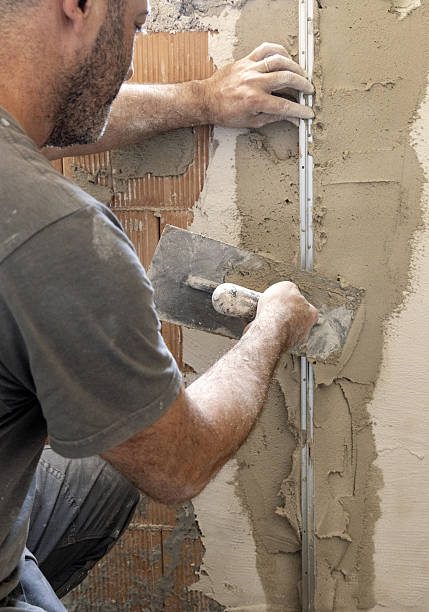 istock Craftsman uses a float trowel and cement to plaster a house wall. Construction process 2224311512