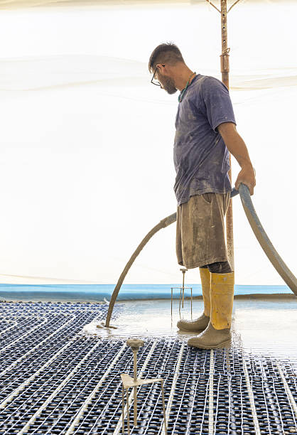 istock Man pouring concrete over floor heating installation in a new building. Modern construction system 2224311515