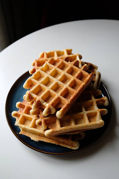 istock Warm, freshly made waffles stacked on a plate in a cozy cafe setting during breakfast hours 2224318162