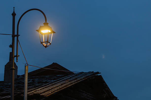 Street lamp casts its warm glow over a quiet street in a European city at night. Soft light highlights the surrounding architecture, creating a serene and timeless atmosphere.