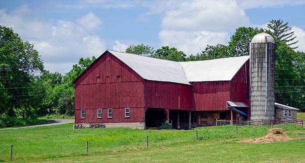 istock Rustic red barn and silo in a green field. 2224324739