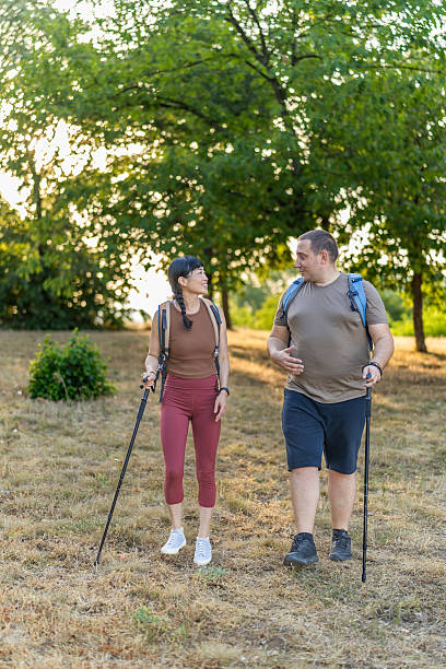 istock Two friends hikers with backpacks are enjoying a conversation and exploration while walking on a sunny forest trail. 2224325405