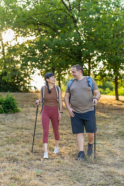 istock Two friends hikers with backpacks are enjoying a conversation and exploration while walking on a sunny forest trail. 2224325936