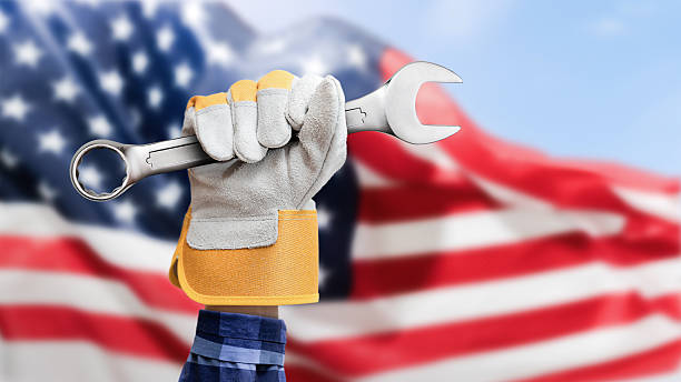 male hand in work gloves holding wrench against American flag background