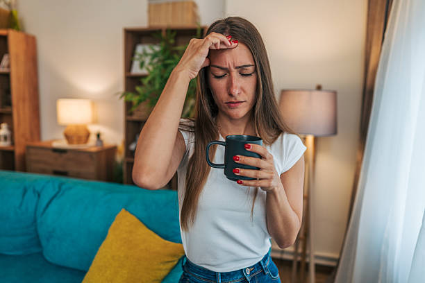 istock Young woman suffering from headache while drinking coffee at home 2224329747