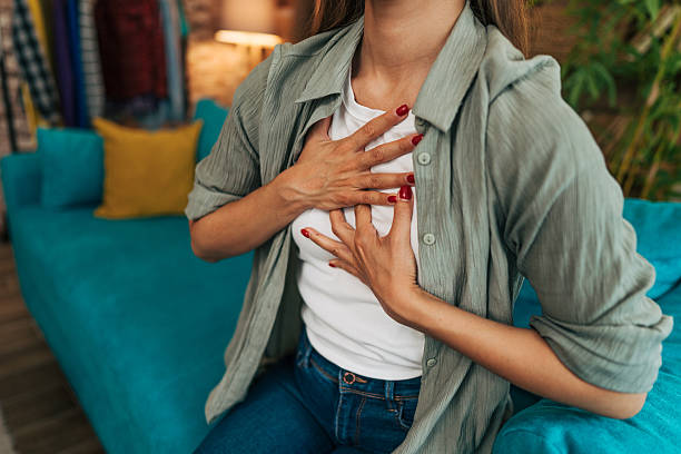istock Woman suffering from chest pain while sitting on sofa at home 2224330841
