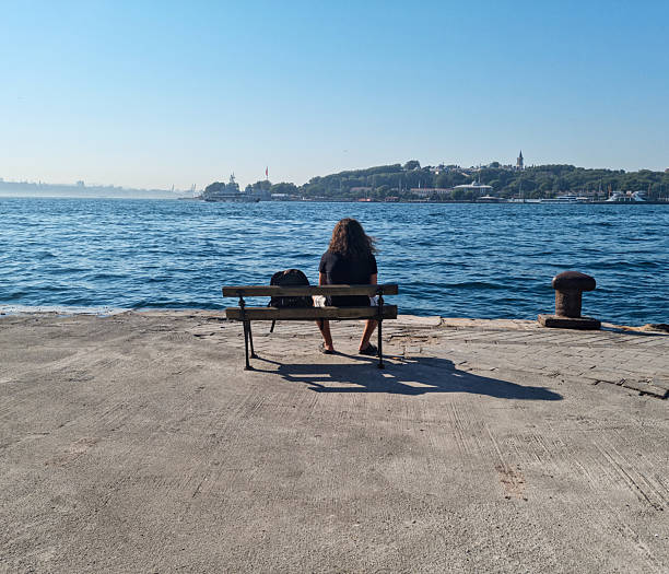 Young man sitting on a bench, looking at the sea