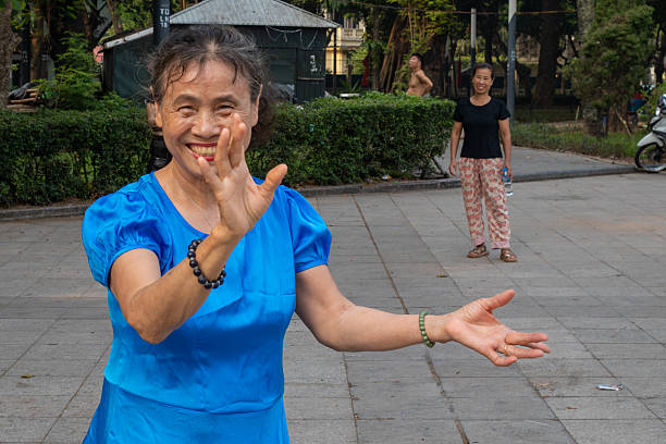 A retired woman in a blue dress dances for eraly morning exercise in Lenin Park, Hanoi, Vietna,.