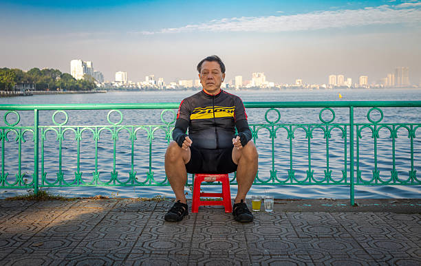 A middle aged Vietnamese man dressed in cycling gear rests on a Sunday morning next to the West Lake in Hanoi, Vietnam.