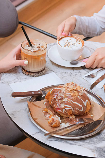 istock Cappuccino and Iced Latte with Chocolate Croissant – Cozy Cafe Table for Two 2224348320