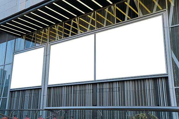 istock Mockups of three blank white billboards framed by a modern building facade, ideal for advertising 2224395507