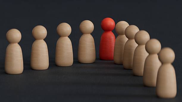 istock A 3d concept graphic depicting a red person standing out from the crowd concept. Rendered against a black background with a soft shadow and reflection to enhance the 3D. 2224400245