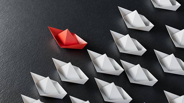 istock Different business concept.new ideas. paper art style. creative idea.Leadership concept with red paper ship leading among white.3D rendering on black background. 2224400257