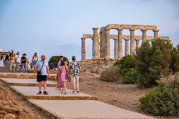 Greece, Sounion - June 20, 2025: Crowds of international tourists explore the iconic Temple of Poseidon at Cape Sounion, Greece—an ancient Doric ruin dramatically set atop cliffs overlooking the Aegean Sea. A popular destination for history lovers and travelers, the site offers stunning panoramic views, especially during sunset.