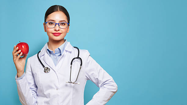 istock Young female doctor holding a red apple 2224403743