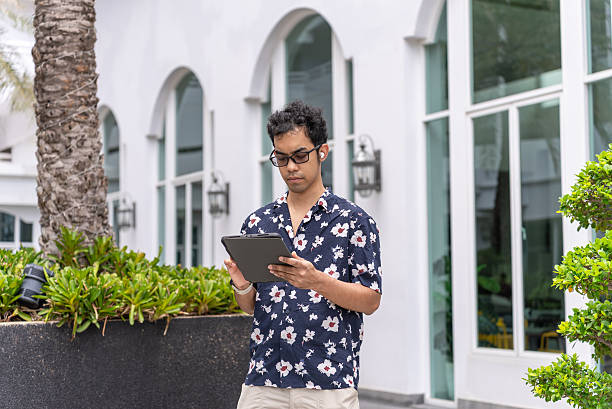 istock Mid-Adult Asian Man Using Digital Tablet Outside Coastal Hotel 2224403992