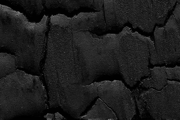 istock A coal-blackened board, split and rough, features a single charred knot viewed from directly above. 2224406290