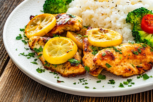 istock Lemon chicken escalopes with rice on wooden table 2224408844
