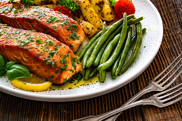 Seared salmon steaks with green string beans and roasted potatoes on wooden table