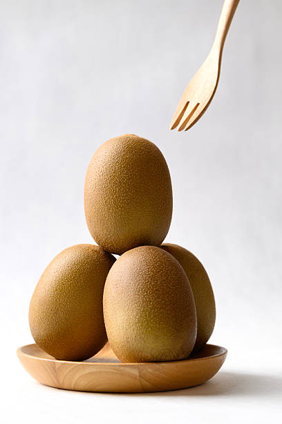 Fresh kiwi fruit with wooden plate and fork on white background, Healthy eating