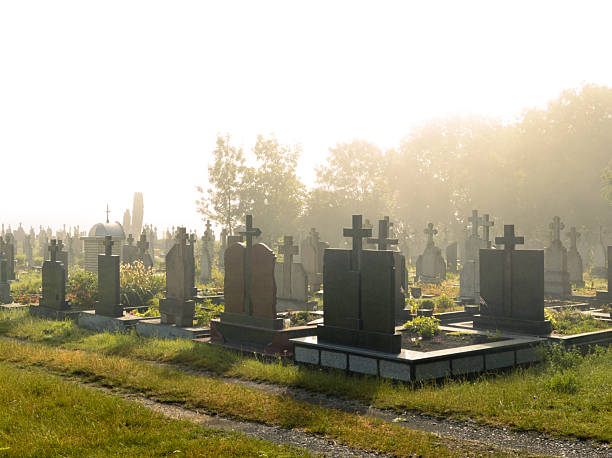 Mystical cemetery in bright morning fog. Graves and crosses in mist and sunlight. Place of burial.