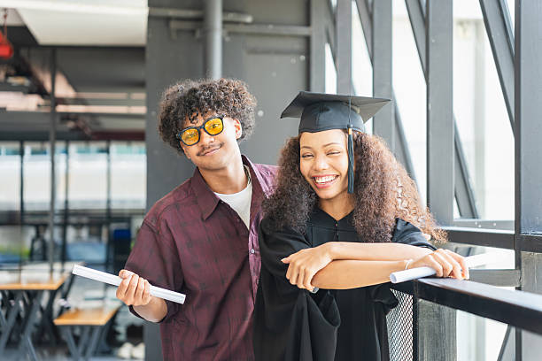 Happy Graduates Celebrate Success on Campus, Joyful Diverse Students on Graduation Day, Young Man Congratulates Female Graduate with Diploma