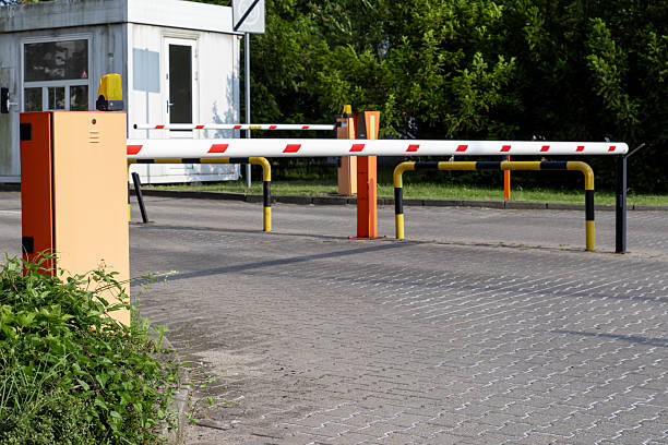 istock Automated parking barrier with a lowered arm and security booth, effectively managing vehicle access and site security at an an entry point 2224424033