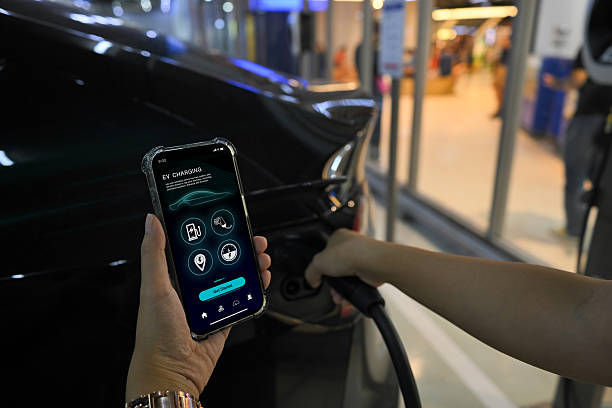 istock Person holding smartphone with an EV charging app while plugging an electric vehicle at charging station 2224424437