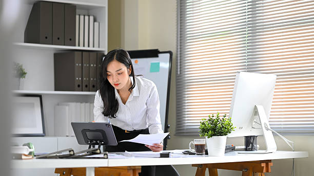 istock Businesswoman focused on reviewing documents and using digital tablet at desk 2224424642