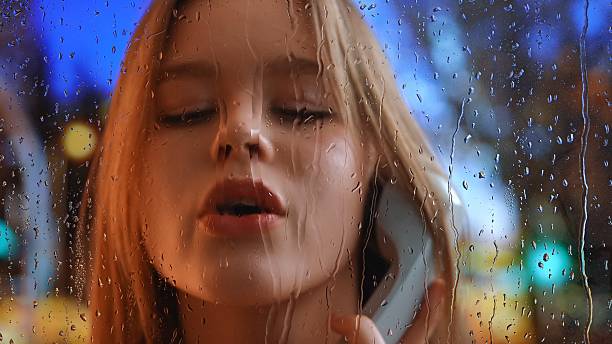 istock Young Woman Talking on Phone with Rainy Window Background 2224424925