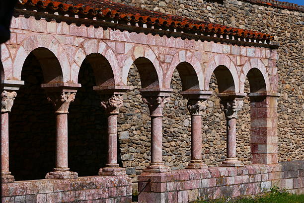 Ancient stone arches of a historic building casting dramatic shadows, highlighting architectural detail and the rugged texture of the wall, evoking a sense of history and weathered strength