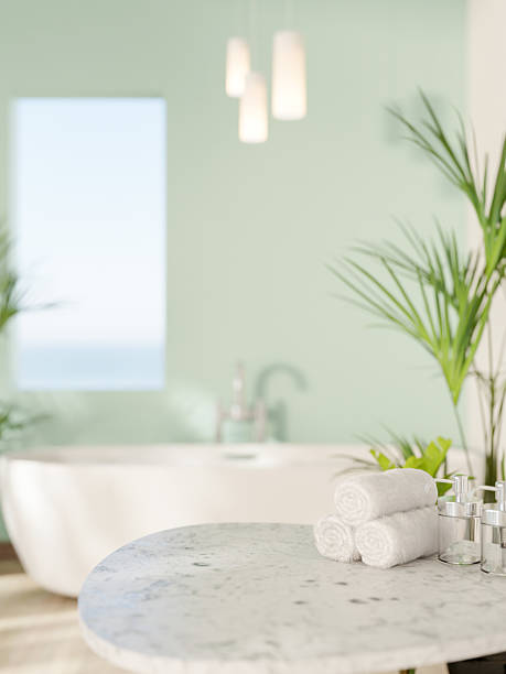 istock Marble stool table with towels and white ceramic bathtub near green mint wall with rectangular hole. 2224434212