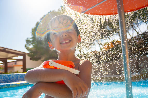 istock Happy child playing under water shower in swimming pool 2224435396