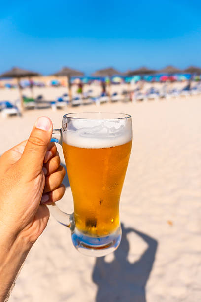 istock Tourist holding a cold beer on a sunny beach 2224435458