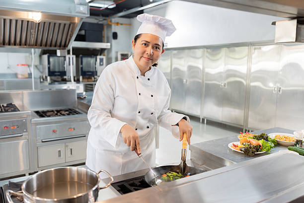 istock Midlife Asian Female Chef Smiling While Cooking in Professional Kitchen 2224438066