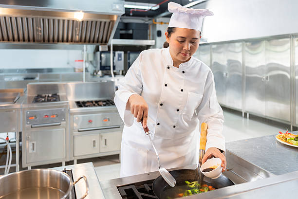 istock Mid-Age Asian Female Chef Focused on Cooking in Commercial Kitchen 2224438100