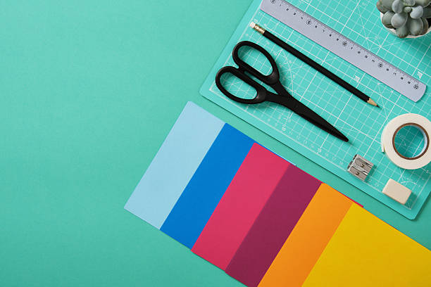 Workspace for paper crafts. Turquoise cutting mat, colored paper, pencils, tape, ruler, scissors. Space for your text.