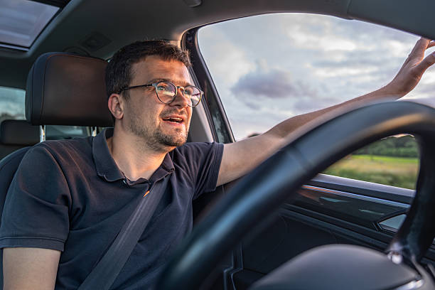 istock Smiling driver. Open window ride. Sunset in car interior 2224439764