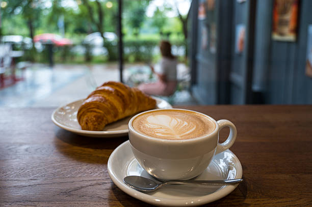 istock Cappuccino and croissant on cafe table with blurred background 2224440665
